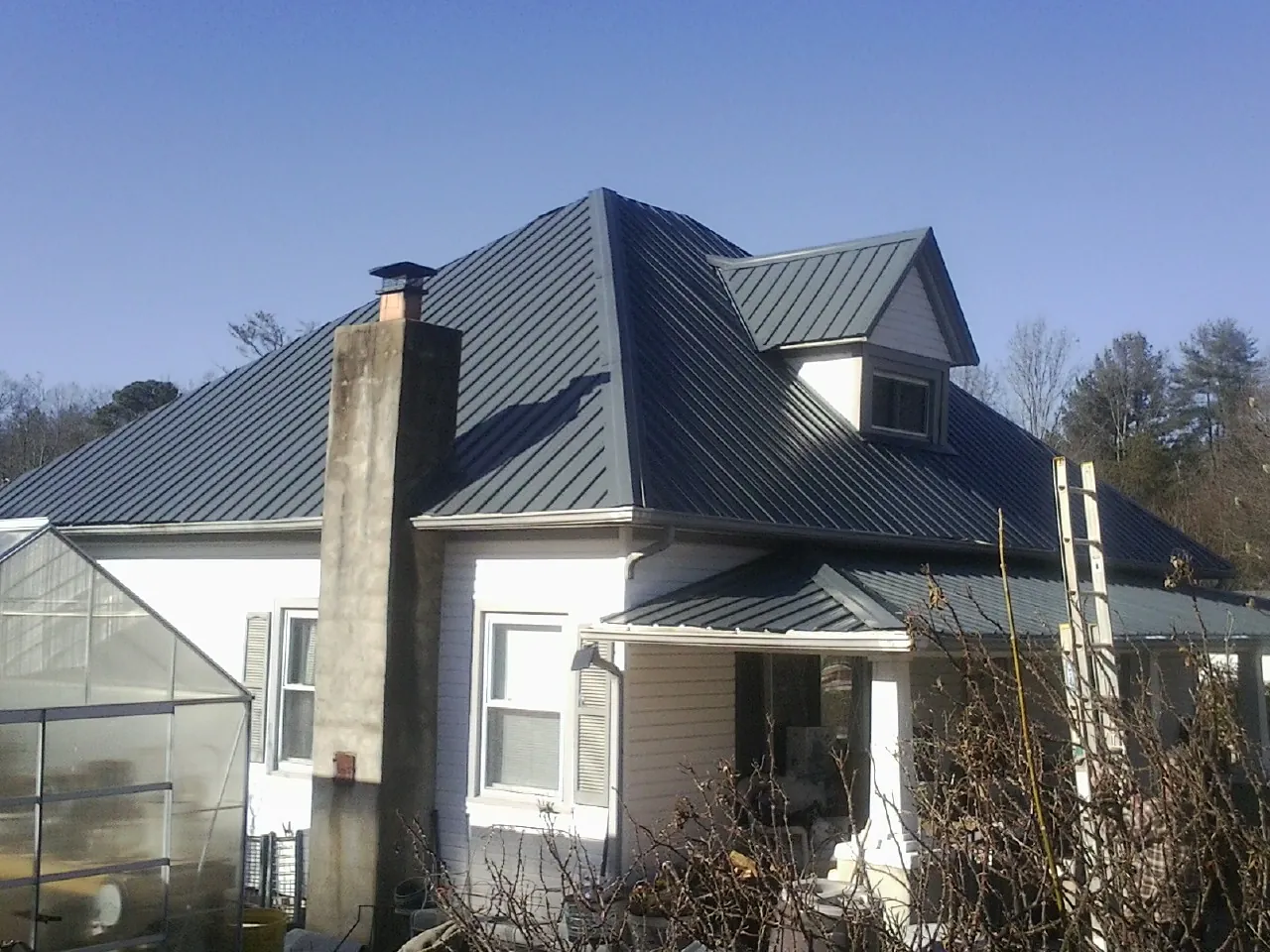 Dark blue standing seam metal roof on a white farmhouse with dormer — Slate & Tile Roof Repair by Roofing Brothers in Graysville
